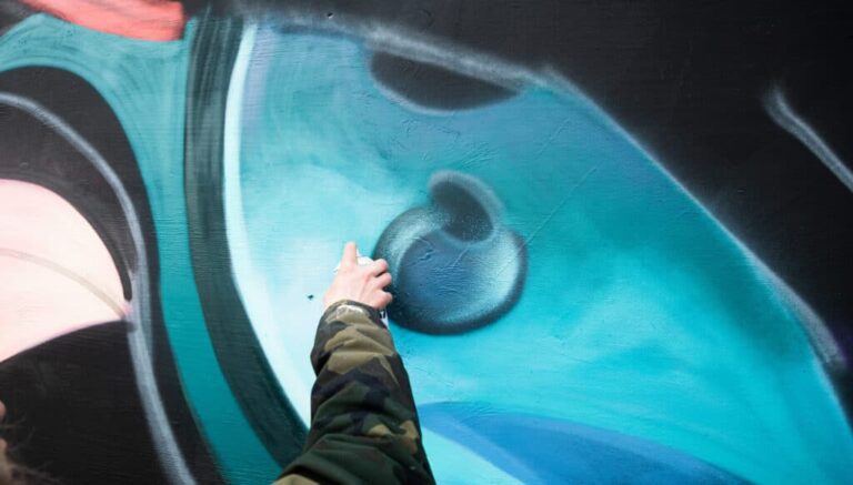 Hand spraying colored graffiti on a wall
